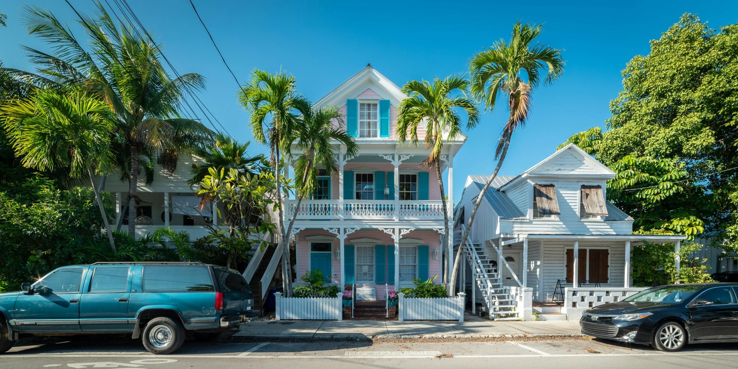 Colorful historic houses with palm trees along a sunny street in Key West, Florida.