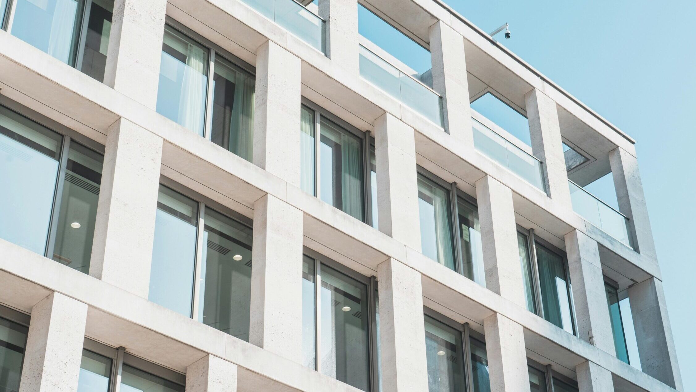 Contemporary office building with glass and concrete design, viewed from a low angle against the sky.